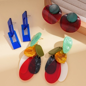 Three pairs of colorful geometric acrylic earrings with silver needles on a display stand