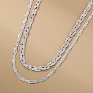Macro view of silver woven snake chain necklace featuring a layered metallic braided design