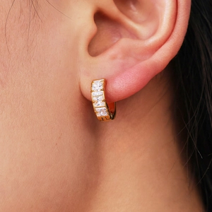 Gold plated stainless steel hoop earrings with four square-cut zircons worn on ear