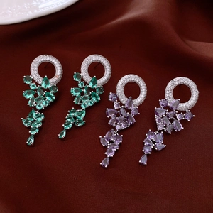 Close-up of fringe earrings with cubic zirconia and teardrop gems in green and purple