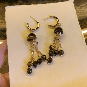 Detail view of ethnic fringe earrings with tiger eye beads and silver needle tassels