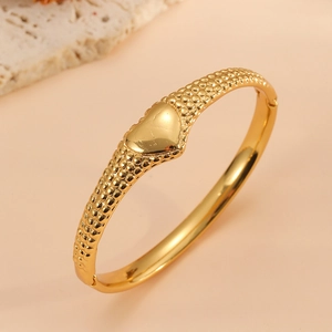 Gros plan d'un bracelet en acier inoxydable plaqué or 18k avec cœur et textures sphériques