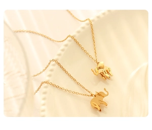 Detailed view of two 18K gold plated elephant pendant necklaces on a ceramic plate