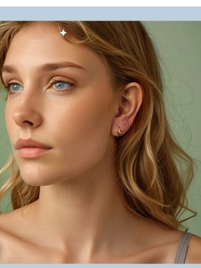 Close-up of elegant gold star hoop earrings worn by a model in a natural setting