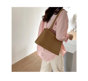 Close-up of brown leather shoulder bag texture and stitching detail for women