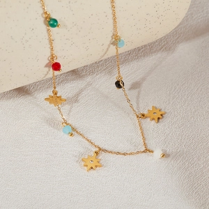 Macro detail of gold star pendants with colorful beads on a fine steel chain