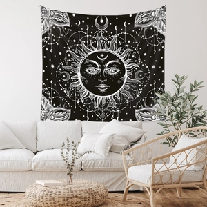Detail of sun and moon bohemian tapestry hanging on a white wall above a modern sofa