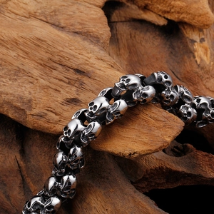 Macro shot of silver stainless steel skull bracelet links on a rustic wooden surface