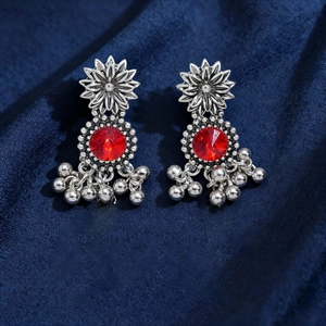 Detailed macro view of vintage silver flower earrings with red gemstone and tassels