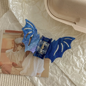 Detail of bat-shaped hair claw clip in translucent blue glitter resin with star-like finish