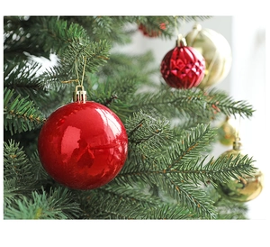 Close-up of shiny red and gold Christmas ornaments with embossed patterns hanging on a tree