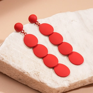 Detail view of red matte geometric oval layered drop earrings on a white stone background