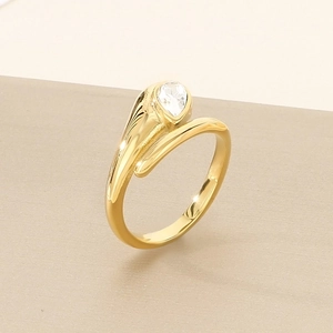 Macro shot of gold-plated knotted ring with pear-cut teardrop diamond on a soft background