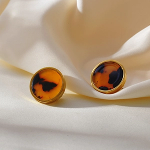 Macro detail of round leopard print earrings with a polished gold metal border