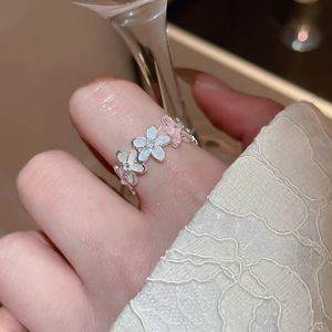 Détail d'une bague florale avec pétales en émail dégradé et accents de zircon sur la main
