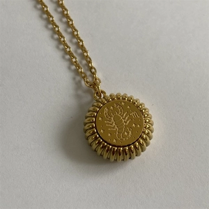Golden Scorpio constellation pendant necklace with sunburst texture on a minimalist chain