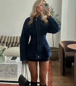 Detailed view of dark blue waist-cinched denim jacket with long sleeves and lapel collar