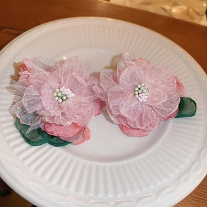 Elegant pink lace flower earrings with green leaves and bead stamens on ceramic plate