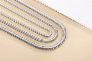 Détail de quatre chaînes serpent argentées plates et souples avec un éclat métallique