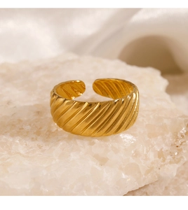 Close-up of golden textured croissant ring on a stone base with creamy fabric background