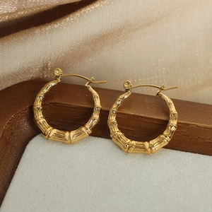 Elegant gold bamboo-jointed U-shaped hoop earrings on a luxury velvet display tray