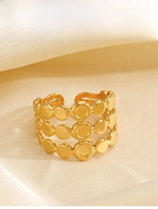 Dettaglio di un anello aperto dorato a tre strati di puntini su sfondo di seta crema