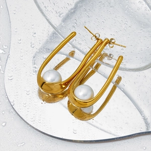 Minimalist gold U-shaped earrings with pearls on wet glass surface for a vintage look