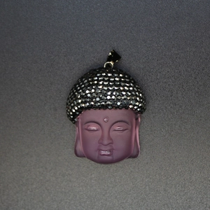 Macro shot of purple translucent crystal Buddha head pendant with black rhinestones