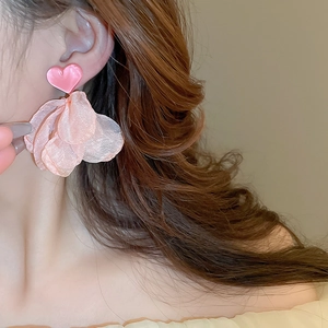 Detailed view of pink mesh petal heart earrings worn by a model in soft light