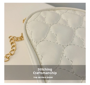 Detail of white PU leather heart quilted stitching and elegant gold chain strap