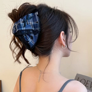 Detail of blue plaid bow hair claw with black lace trim on model back of head