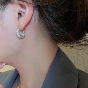 Close-up of model wearing silver U-shaped earrings with micro-set zircon stones