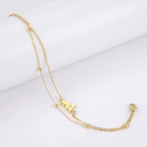 Close-up of double-layered gold bracelet with tiny beads and a cute cat silhouette charm