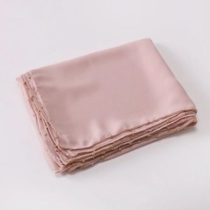 Detail view of pink satin scarf featuring premium golden beaded trim and smooth texture