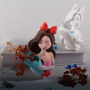 Detailed resin craft of a girl holding a blue flower pot with a red bow and pink dress
