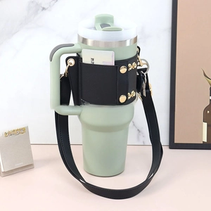 Detail view of mint green 40oz tumbler with black leather sleeve and gold stud accents