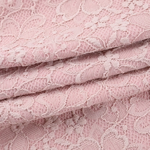 Close-up of pink lace fabric showing intricate floral crochet texture and hollow details
