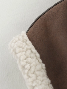 Detail of faux suede vest with brown exterior and soft cream shearling lining texture