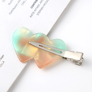 Detailed view of translucent double heart gradient hair clip on an aesthetic book page