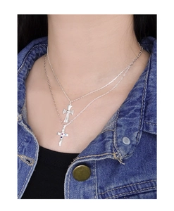 Close-up of a silver double-layered cross necklace with colorful zircons on a model