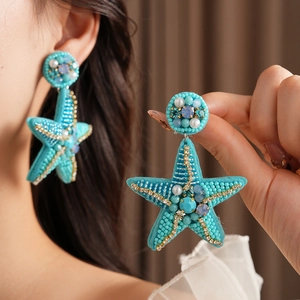 Detailed view of turquoise starfish earrings with hand-woven beads and pearls