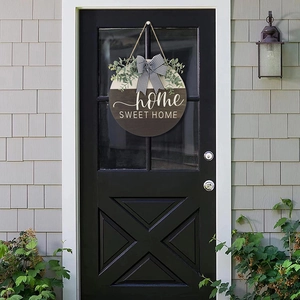 Detail of round wooden door sign with home SWEET HOME text and striped ribbon bow