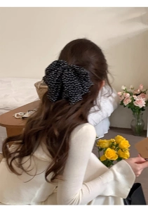 Detailed view of a French retro polka dot chiffon bow hair clip worn by a model