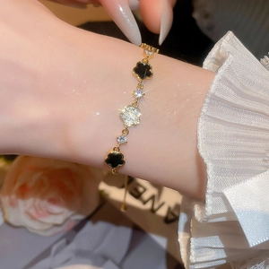 Detail of adjustable gold bracelet featuring acetate zircon flower charms on a female wrist