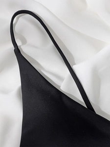 Detail of silk satin bikini top showing thin black straps and glossy fabric texture