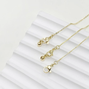 Detail of adjustable 14k gold lobster clasp with box chain and fine O-chain links