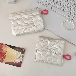 Detail of silver quilted heart pouches with pink lanyards and metallic texture finish