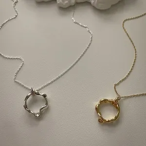 Close-up of wavy irregular silver and gold necklaces on a minimalist textured background