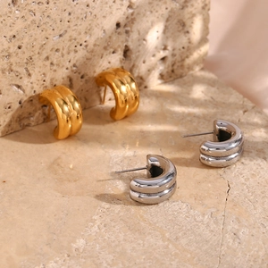 Polished gold and silver double-layered C-shape hoop earrings on a textured stone base