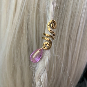 Close-up of golden spiral hair jewelry with pink teardrop crystal on braided blonde hair